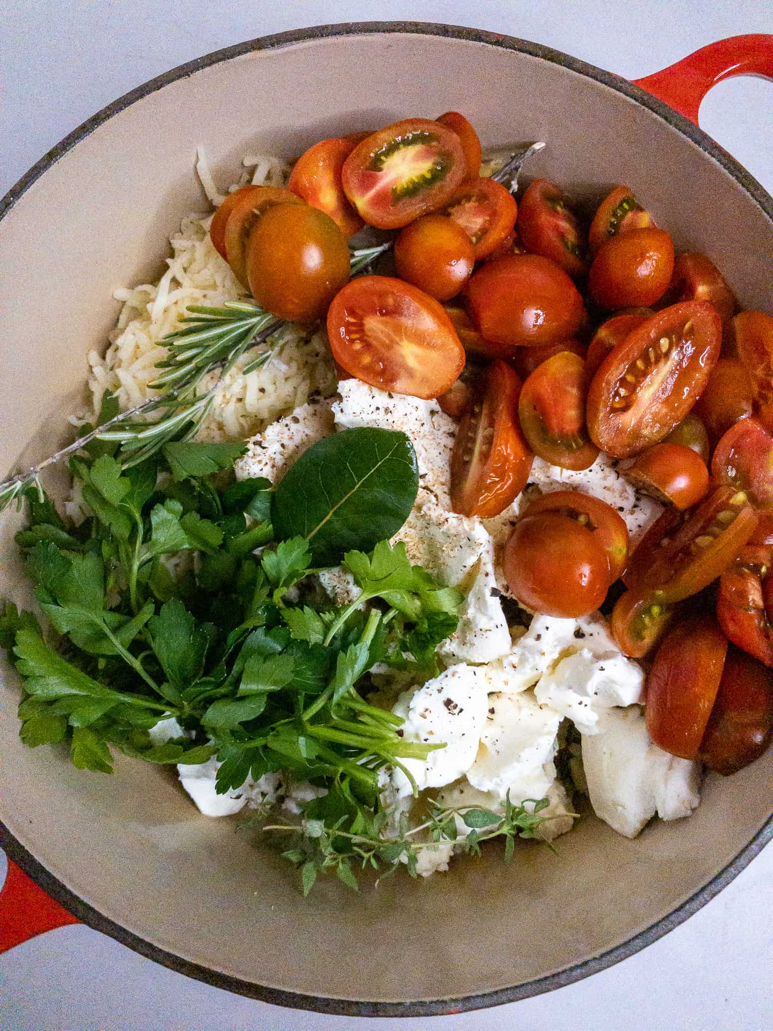 Tomatoes, herbs, cheeses, and pasta layered in a pot